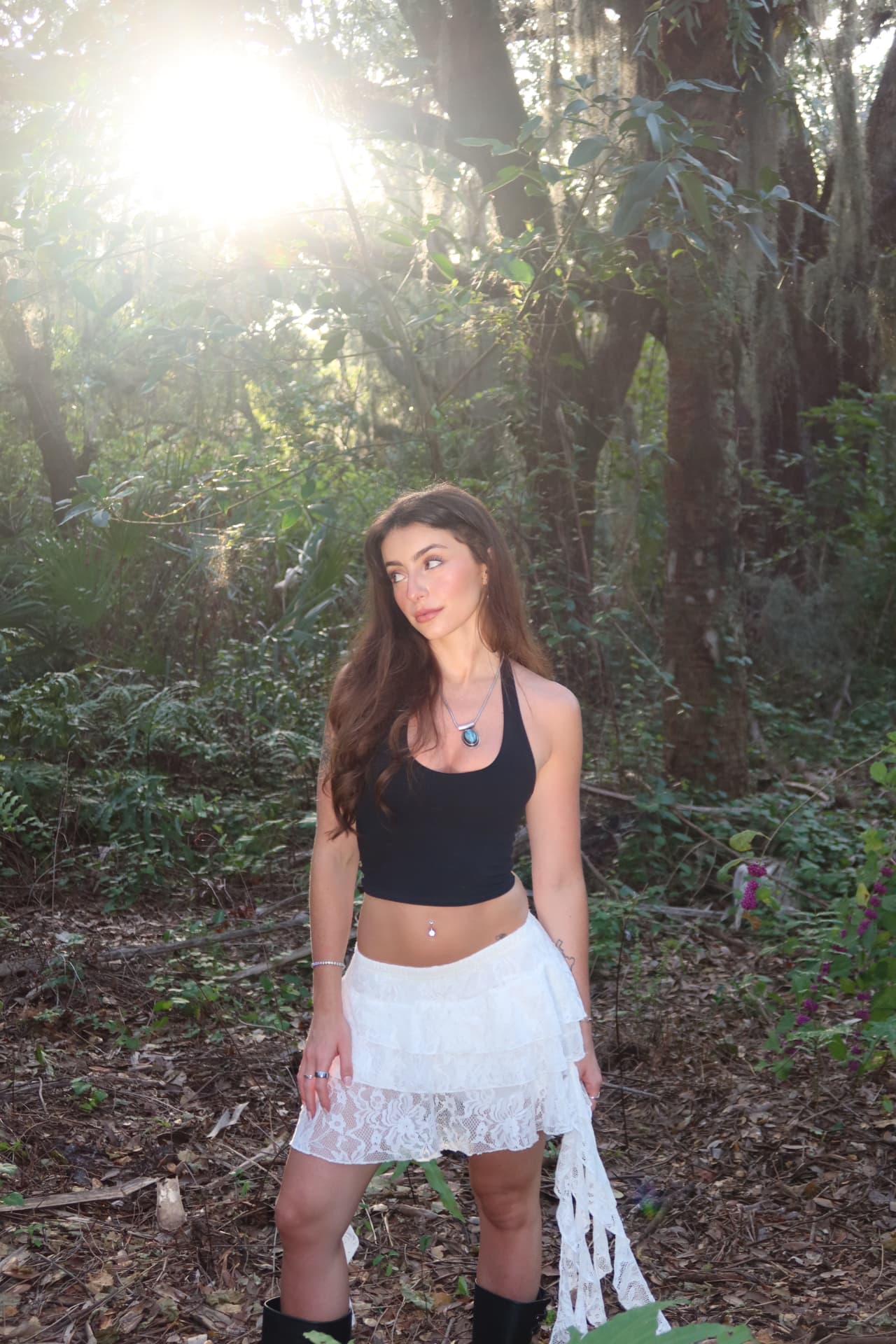 Portrait looking away, sun flaring through the tree canopy