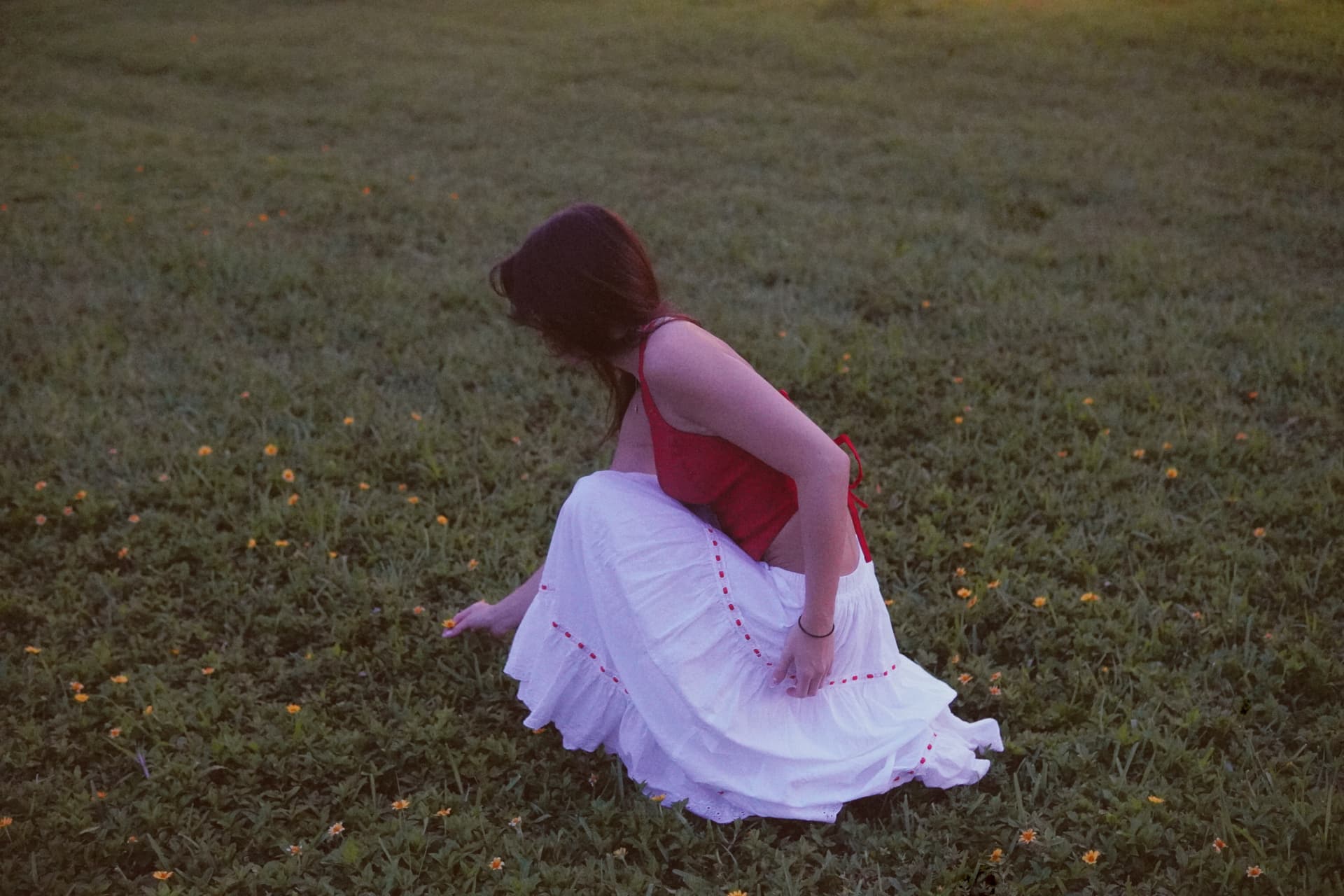 Crouching low in a field of small yellow flowers as the skirt spreads across the grass